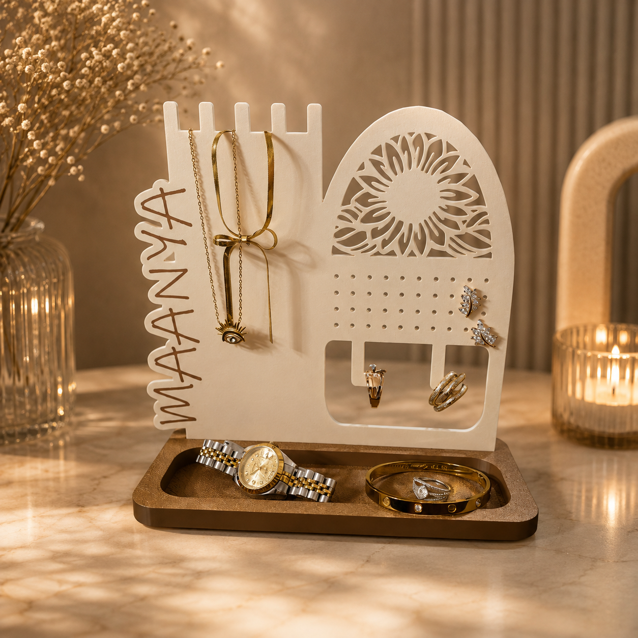 A white jewelry organizer stand with cutout details and hanging slots, placed on a wooden tray on a marble tabletop. The stand holds gold-toned jewelry, including necklaces, rings, and earrings, with a watch and bracelet resting in the tray below.